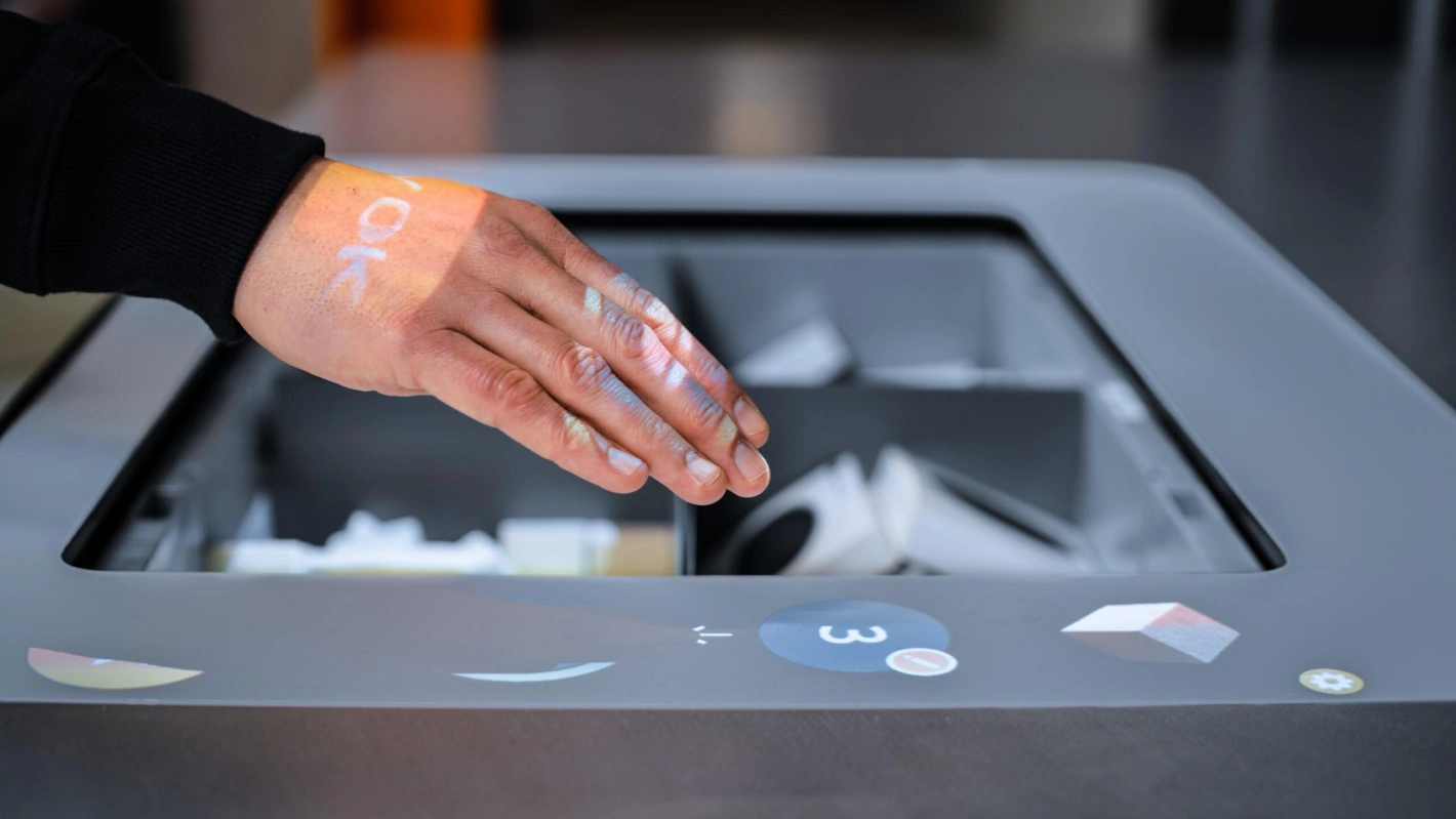 Der Picking Assistent IPA von Kardex hat eine 3D-Kamera, die Bewegung von Hand und Finger erkennt, sodass virtuelle Knöpfe dargestellt werden können.. Foto: Kardex